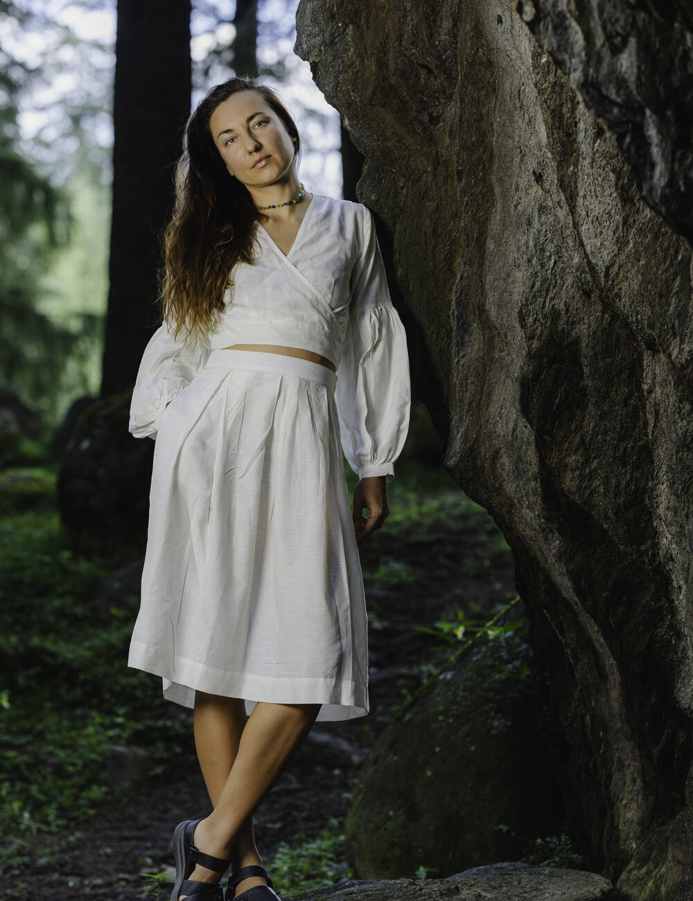 A woman in a natural setting, wearing a long, flowy white skirt in soft cotton linen. She is 5'8" tall and wearing a size M.