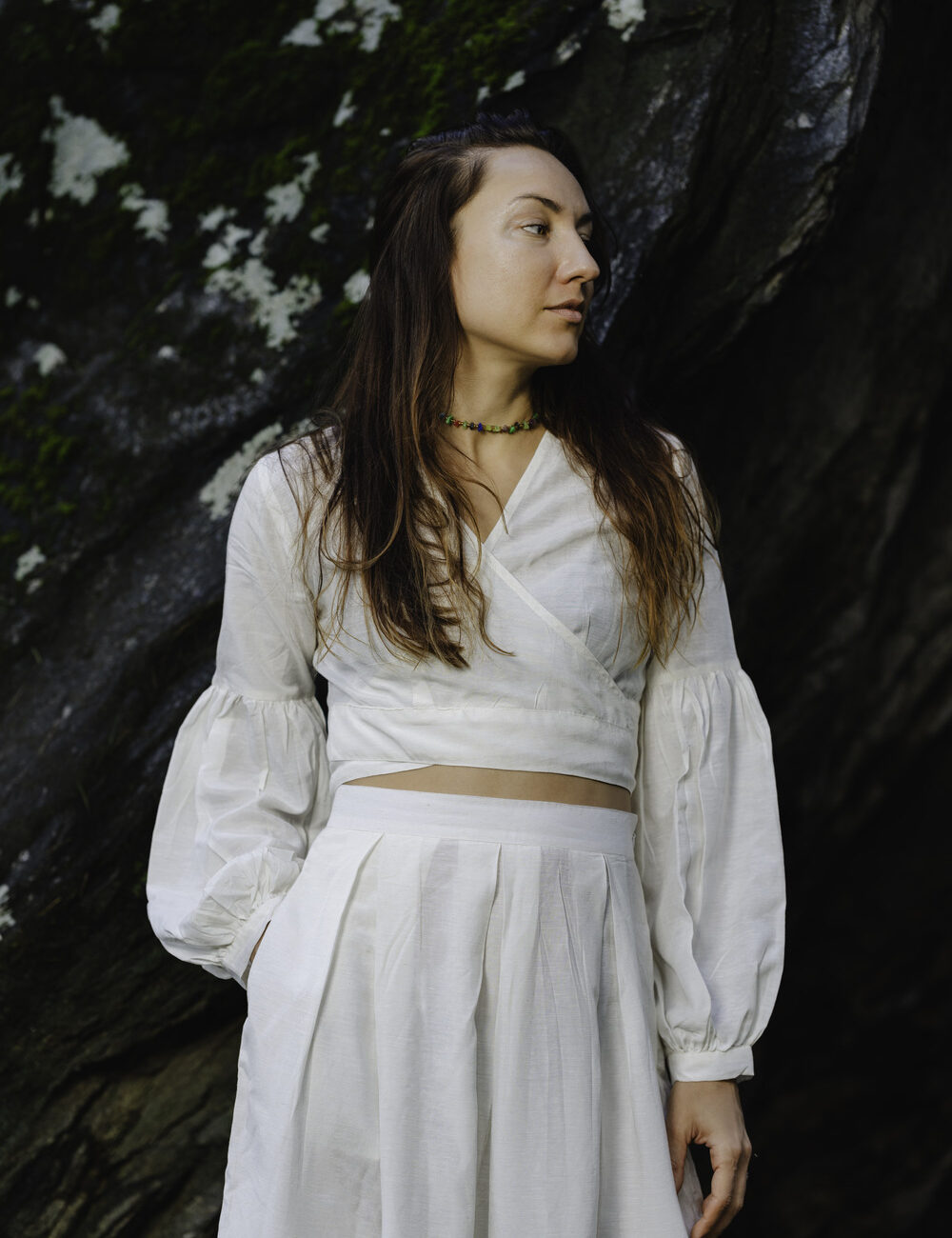 A woman standing outdoors, wearing an off-white cotton linen wrap-around crop top. She is 5'8" tall, wearing a size M.