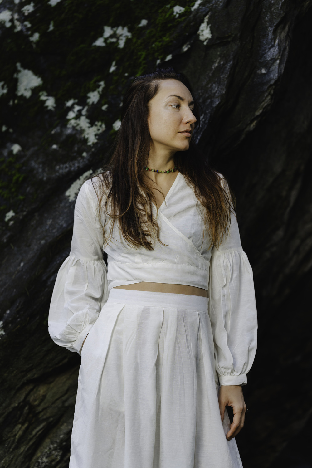 A woman standing outdoors, wearing an off-white cotton linen wrap-around crop top. She is 5'8" tall, wearing a size M.