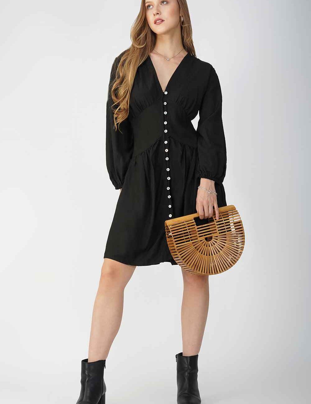 The model wearing a black dress with long sleeves, a button-down front, and a fitted waist.