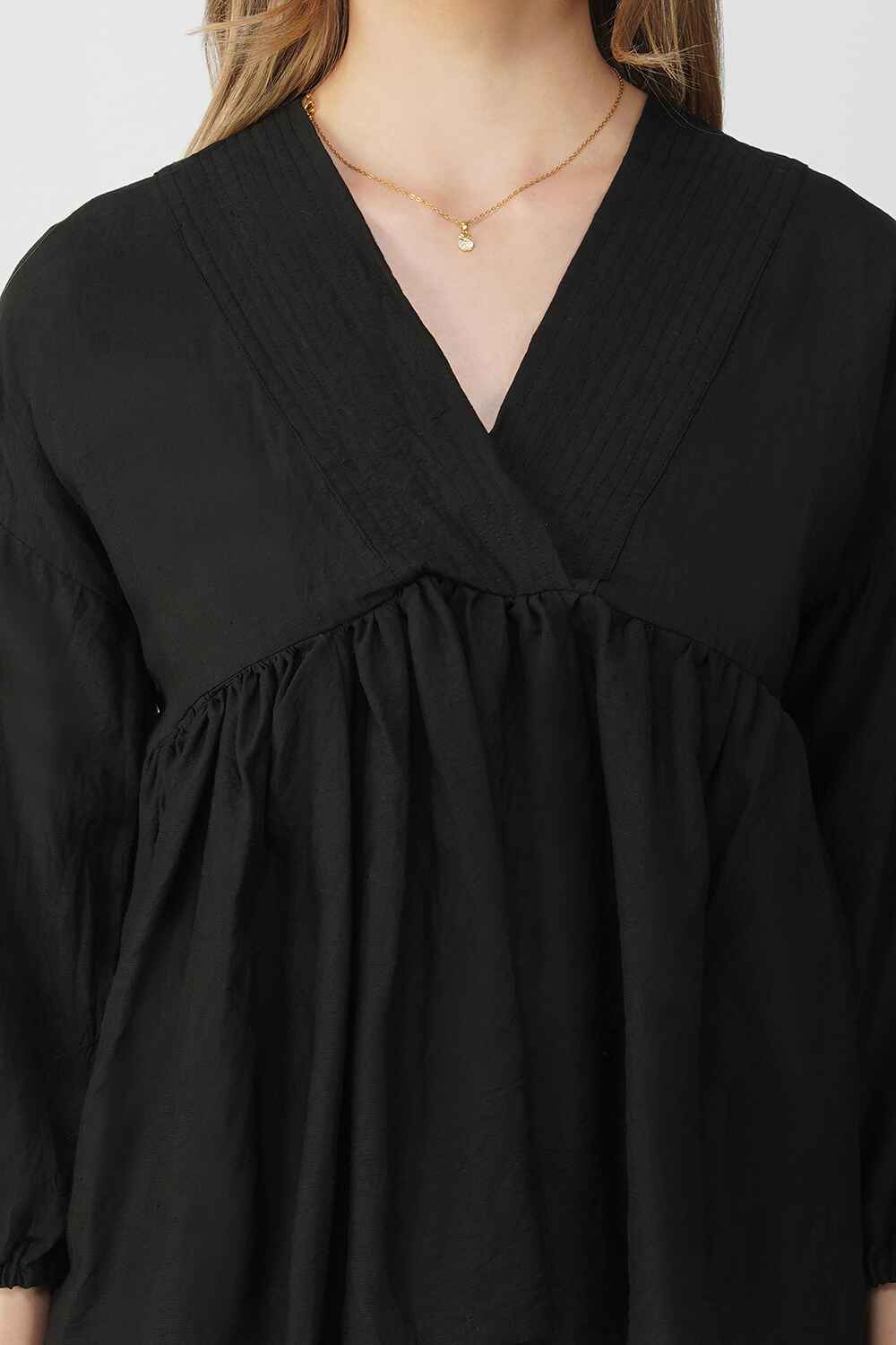 Black cotton-linen peplum top with a v-neckline and relaxed, flowy structure.