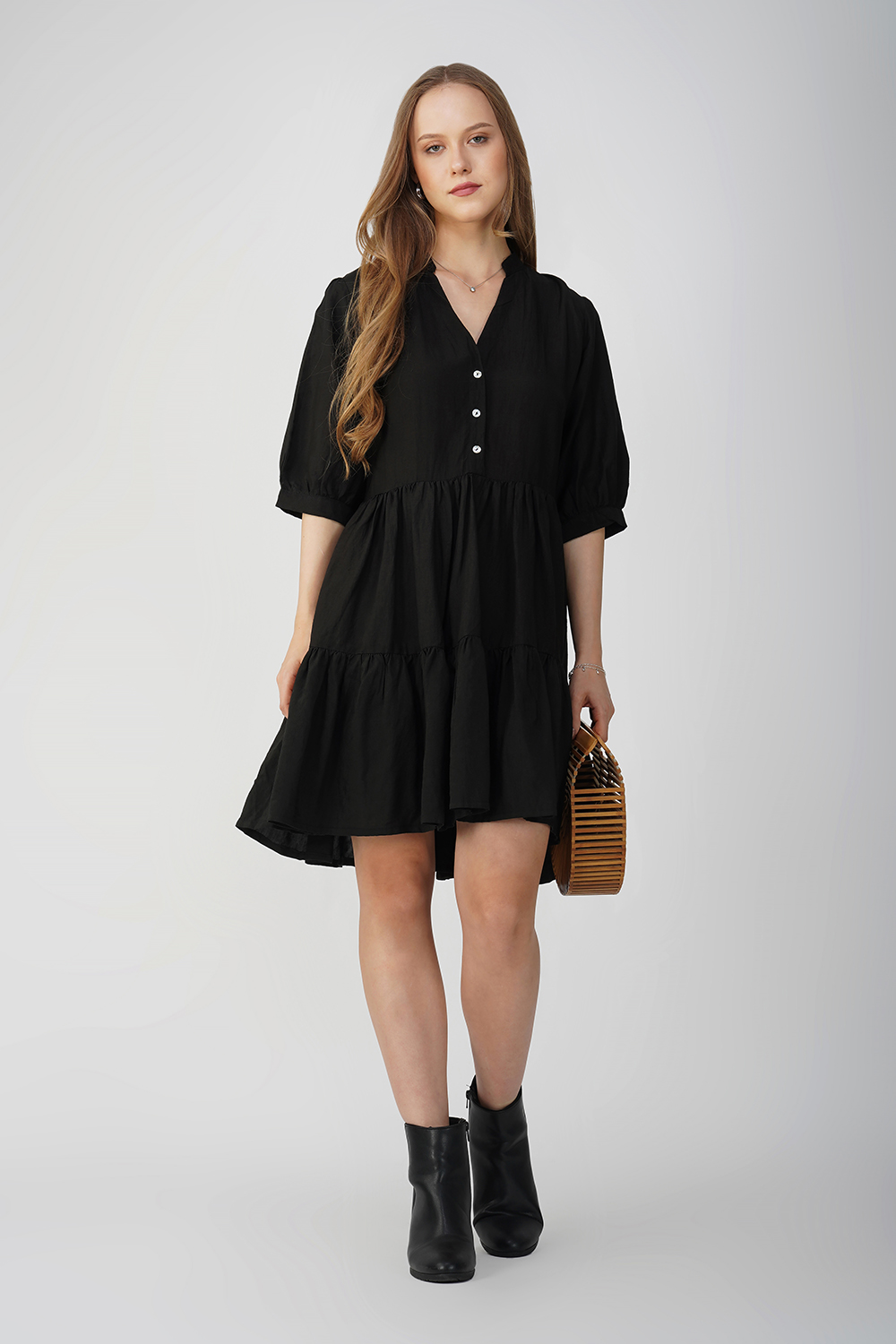 Model wearing a casual black cotton linen tiered dress with a relaxed fit and button-down detai